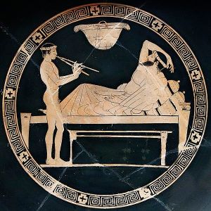 Un joven desnudo toca el aulos para el comensal de un banquete. Copa roja ática, pintor de Eveón, 460-450 a. C.
